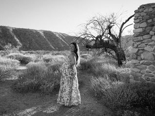 Joshua Tree maternity photography showing the dress flowing dramatically in the desert breeze, symbolizing movement and new beginnings.
