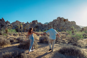 Expecting couple walking hand in hand through Joshua Tree desert at sunset near Palm Springs maternity session