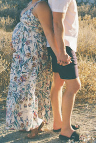 Close-up of expecting couple holding hands beside pregnant belly during a Joshua Tree maternity session.