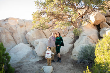 Family of three expecting a baby, surrounded by pine trees and desert rocks during Joshua Tree mini session at Hemingway.