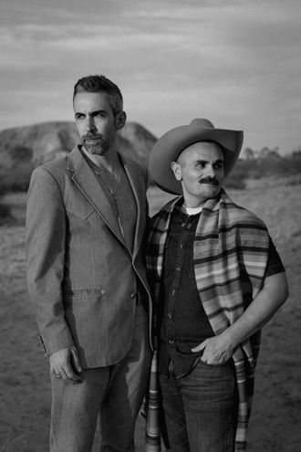 Same-sex couple standing together in the desert during a Joshua Tree portrait session, documentary-style photography in the High Desert
