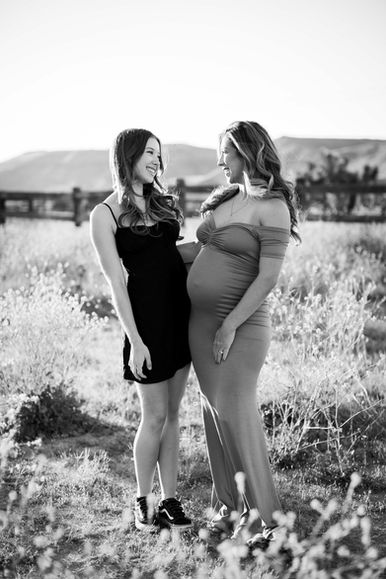 Pregnant mother and teenage daughter smiling at each other during maternity session in Pioneertown near Joshua Tree