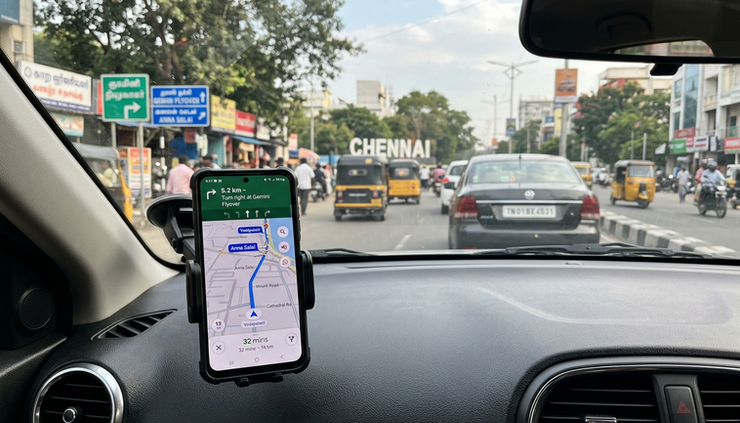 Close-up view of a phone showing a map route beside a car dashboard.