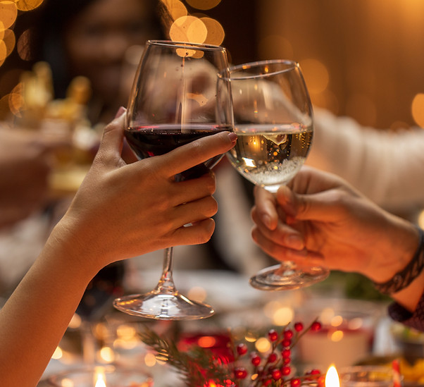 holidays, drinks and celebration concept - close up of hands toasting wine glasses at dinn
