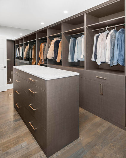 Custom walk-in closet in a Denver home with full-height storage, built-in shelves, and a center island built by VOGO Cabinets