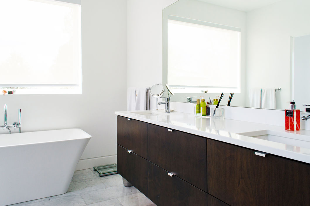 Modern bathroom with dark wood vanity cabinetry, clean white countertop and large mirror by VOGO Cabinets