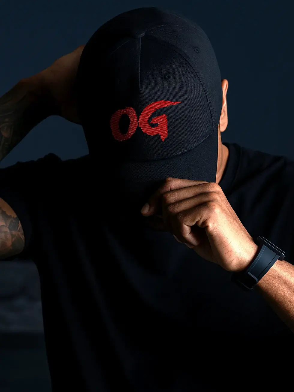 Black cap with red "OG" text, worn by a person in a dark setting.