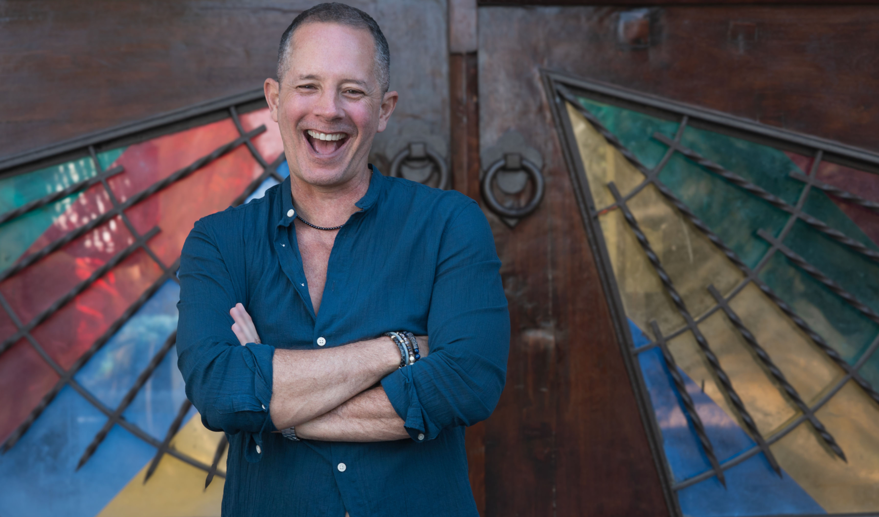 Pablo smiling and laughing in front of artistic stained-glass doors, reflecting warmth, authenticity, and approachable coachi