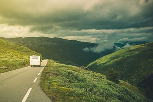 A caravan on the open road in rolling hills with a storm brewing. 