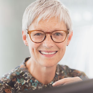 Femme d'âge mûr aux cheveux gris courts et portant des lunettes, fixant la caméra
