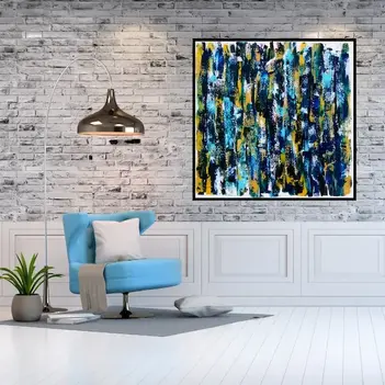 A large, square shaped, blue and gold abstract art piece hanging next to a blue chair on a gorgeous white brick wall. 