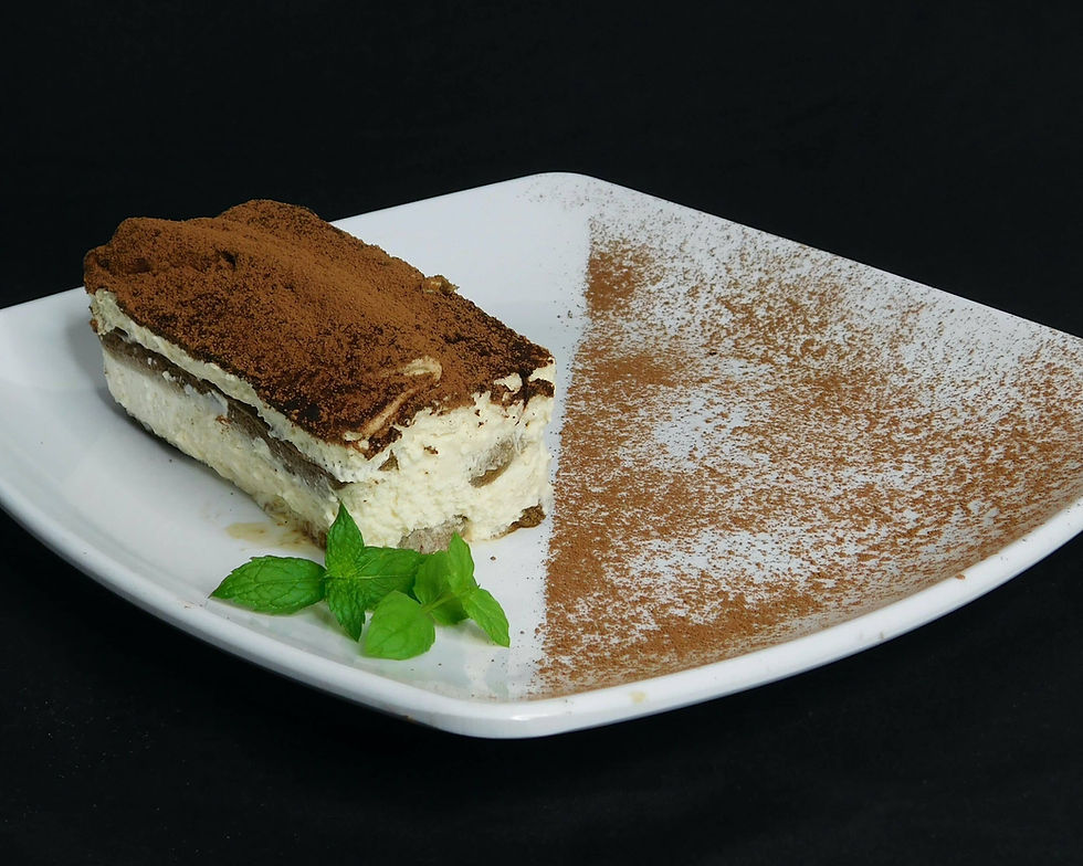 Tiramisu-cake-dessert-with-mint-leaves-and-cocoa-on-white-shallow-plate