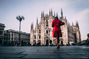 Helena in red dress walking towards Milan Cathedral