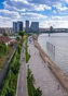 Riverfront promenade with city skyline and people