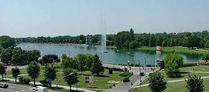 Aerial view of a scenic park with a lake and a tall fountain