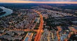 Aerial view of a city at dusk with river and illuminated roads