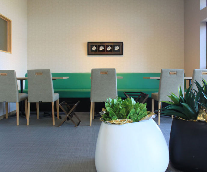 グリーンのソファ席とモダンな観葉植物がある落ち着いたカフェの店内