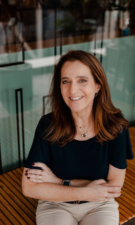 Mulher branca sorrindo sentada e de braços cruzados