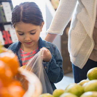 young girl grocery shopping with parent