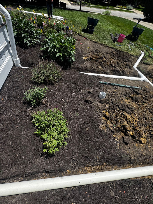 Drainage pipes installed in landscaping beds by Mowments Notice Lawn Services