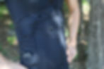 A side view of an athlete wearing the black ElecSuit, showing the EMS technology wiring and control unit tucked into a side pocket. This smart wear is designed as advanced athletic apparel for performance enhancement.