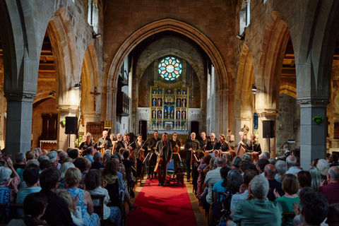 orchestra giving standing ovation to clapping audience in a church