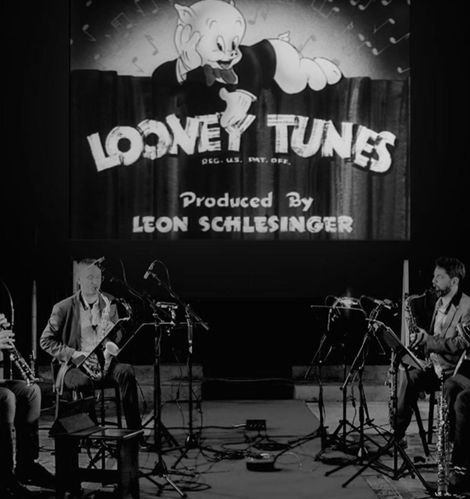 Poster image of Looney Tunes cartoon on big screen with saxophone quartet in front for upcoming concert