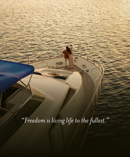 Photo of a couple on board a yacht taking a photo during sunset.