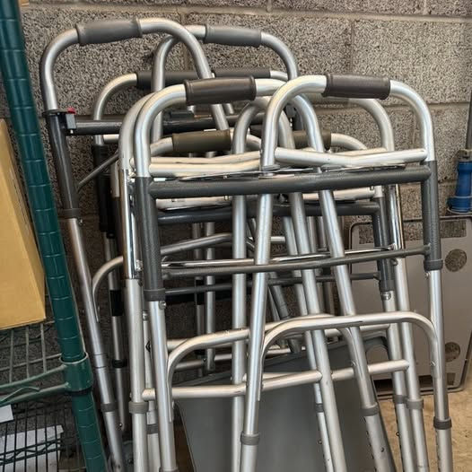 Photo of folded walkers stacked against a wall. These available for check out at the Beyond Barriers Medical Loan Closet in Hutchinson.