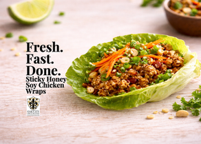 A single chicken lettuce wrap filled with glossy honey soy ground chicken, topped with shredded carrots, green onions, and crushed peanuts, sits on a wooden surface with soft light and open space on the right.