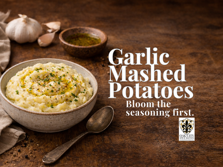 Creamy garlic mashed potatoes in a rustic bowl drizzled with golden garlic oil and herbs, set on a wooden table with text reading “Garlic Mashed Potatoes – Bloom the seasoning first.”