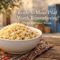 Fluffy long-grain rice pilaf with lightly toasted golden grains and diced onion in a simple ceramic bowl on a rustic wooden table. A sparkling embroidered Mediterranean linen sits beneath the bowl, with a soft-focus courtyard background featuring cream stone walls, blue shutters, and olive tree shadows. Text overlay reads, “Ready to Make Pilaf Worth Remembering? Oak City Spice Blends.”