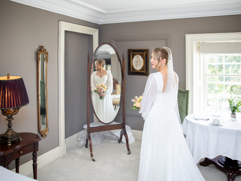 Candid photo of a bride having her hair styled before the ceremony.