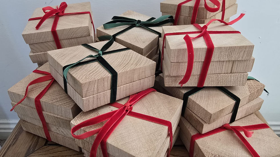 Stacks of handcrafted wooden coasters tied with festive red and green ribbons, arranged neatly on a wooden surface.