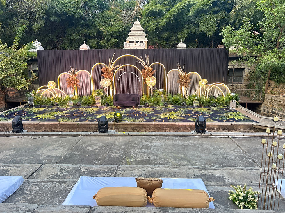 "Glam sangeet stage with black backdrop, floral arches, temple-style accents, and luxe gue