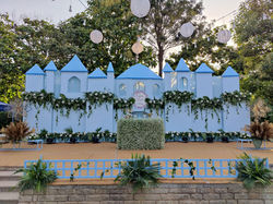 Lavish reception stage decorated in royal blue and gold tones with floral arches, velvet seating, an