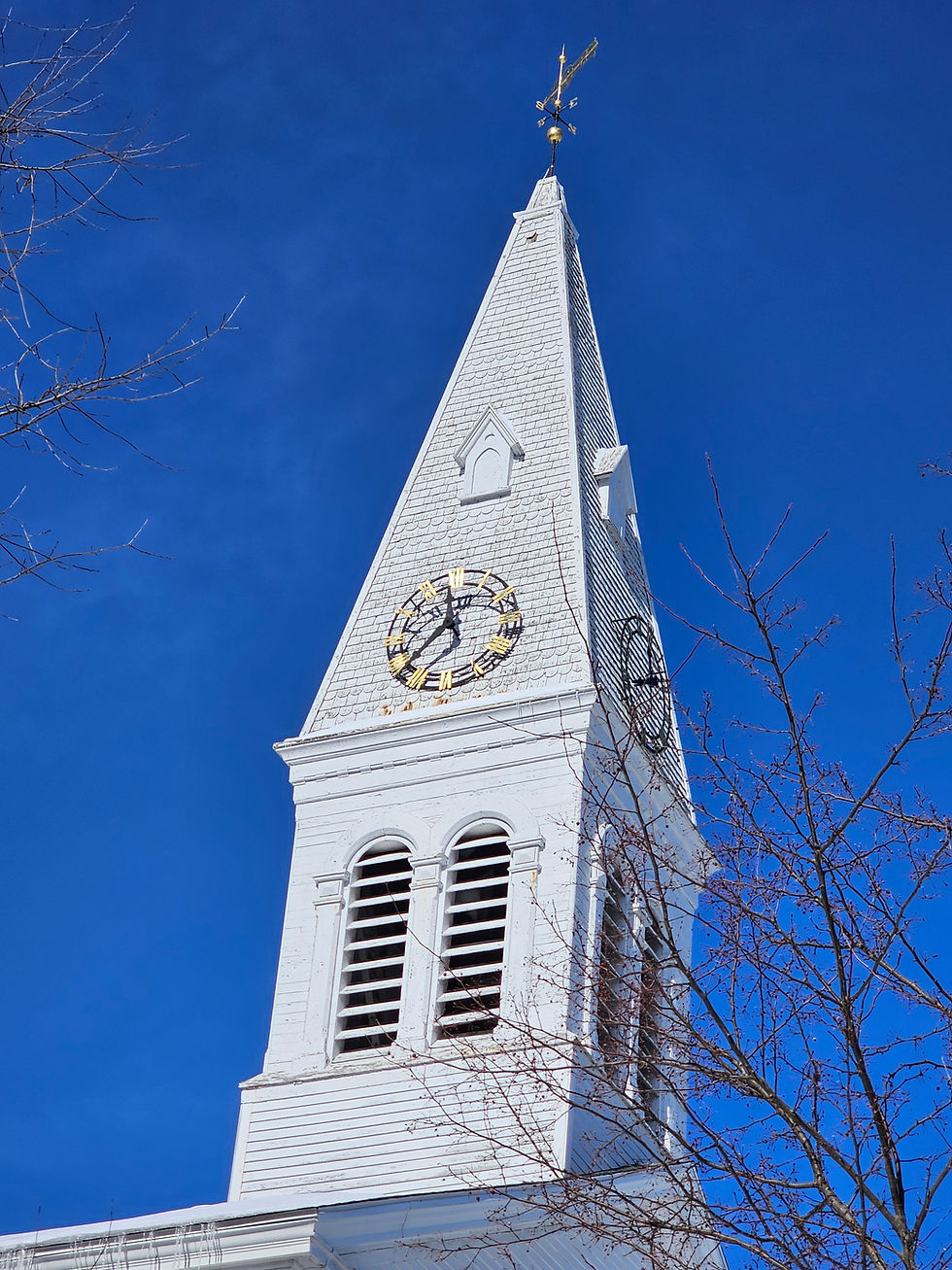A close-up of the historic steeple at Community Congregational Church, UCC of Greenland, NH, rising against a deep blue sky.