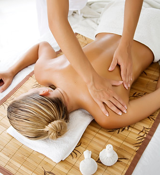 Massage being performed on a womans back, towels under the clients head nad covering them up