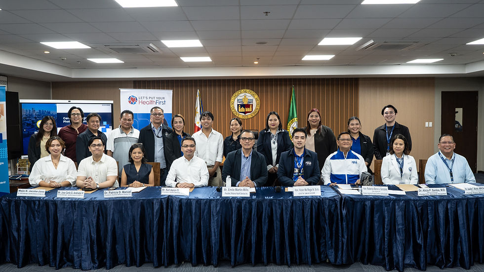 A group of people stand behind a table with nameplates. Banners read "Let's Put Your Health First." The setting is a well-lit conference room. Mayor Vico Sotto
