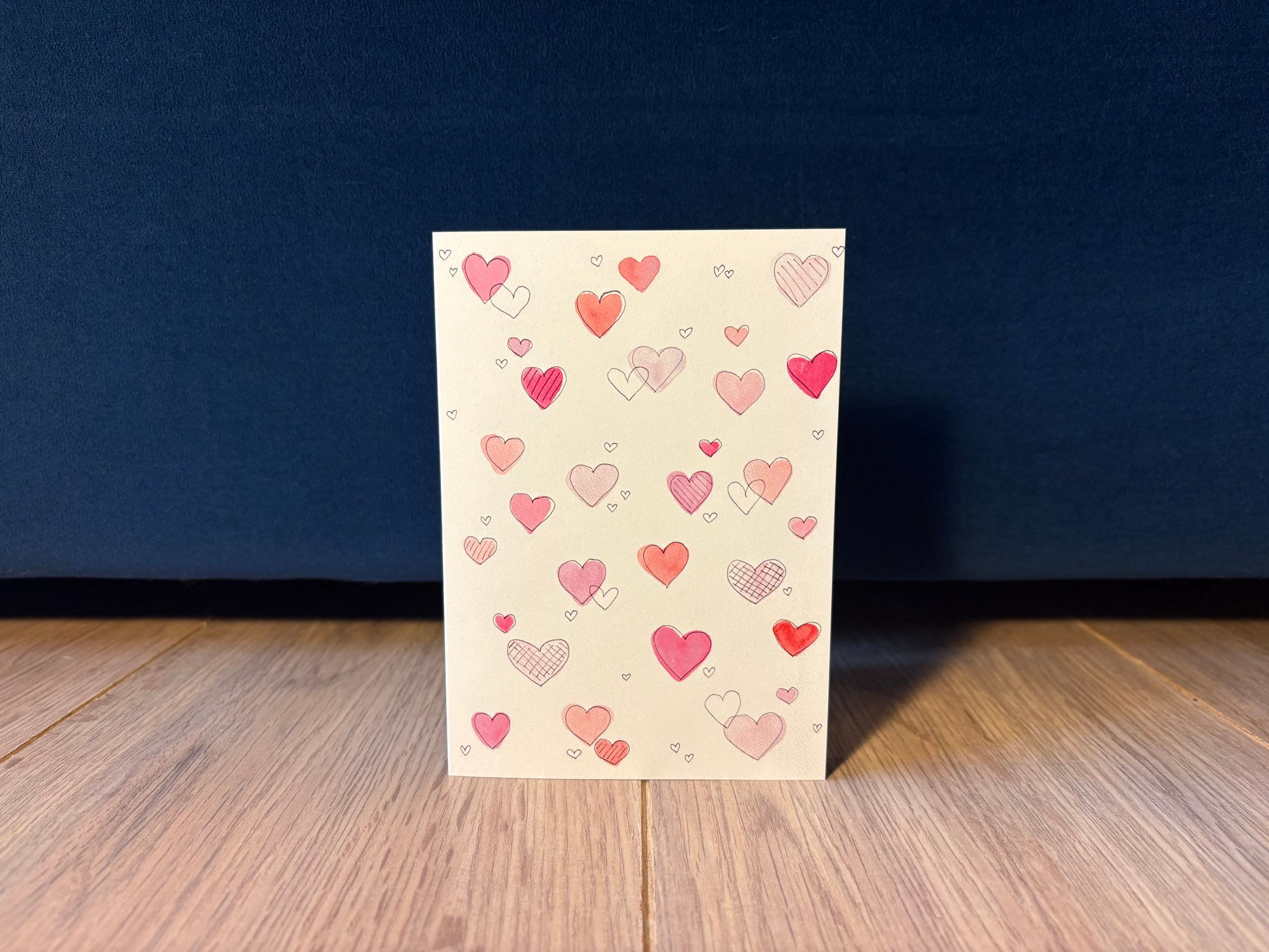 Voorkant wenskaart met hartjes in diverse maten en tinten roze.