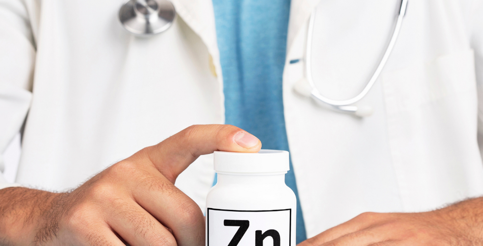 çinko gıda takviyesi kutusunu parmağıyla gösteren doktor