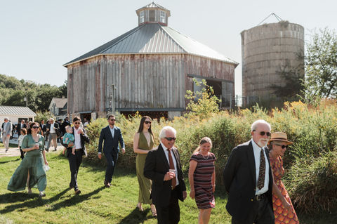 Wedding guests walk behind a historic octagon barn to attend the ceremony.