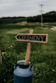 Antique milk can with wooden sign directing guests to the ceremony