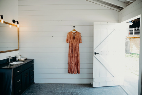 Pink wedding dress hung on white walls in the private suite