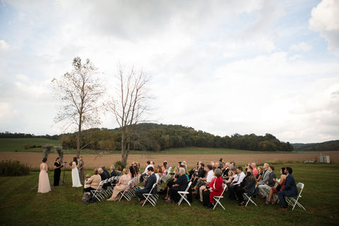 guest sat on white chairs as a couple says their vows