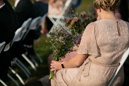 A woman sitting in a sparkling dress holds a bouquet of flowers