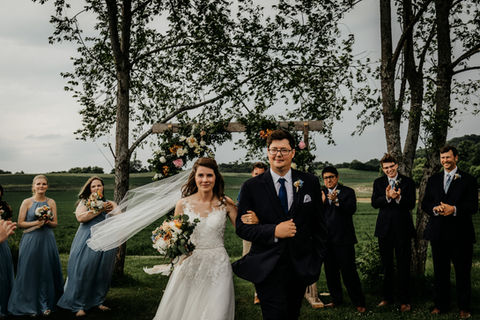 smiling bride and groom walk down the aisle as they leave their ceremony