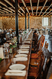 Long wooden table set with white plants and white linens