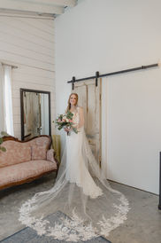 Bride standing in private suite with the train of her veil spread out around her