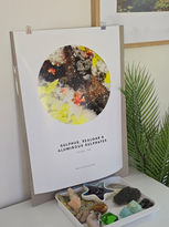 Poster with text and colorful abstract art, with a tray of stones.